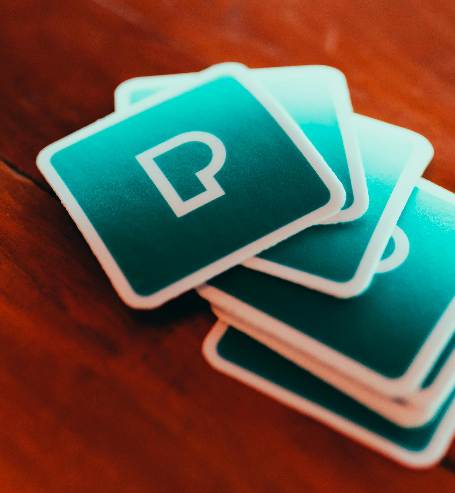 Close-up of a stack of square design cards on a wooden table with a stylish symbol.