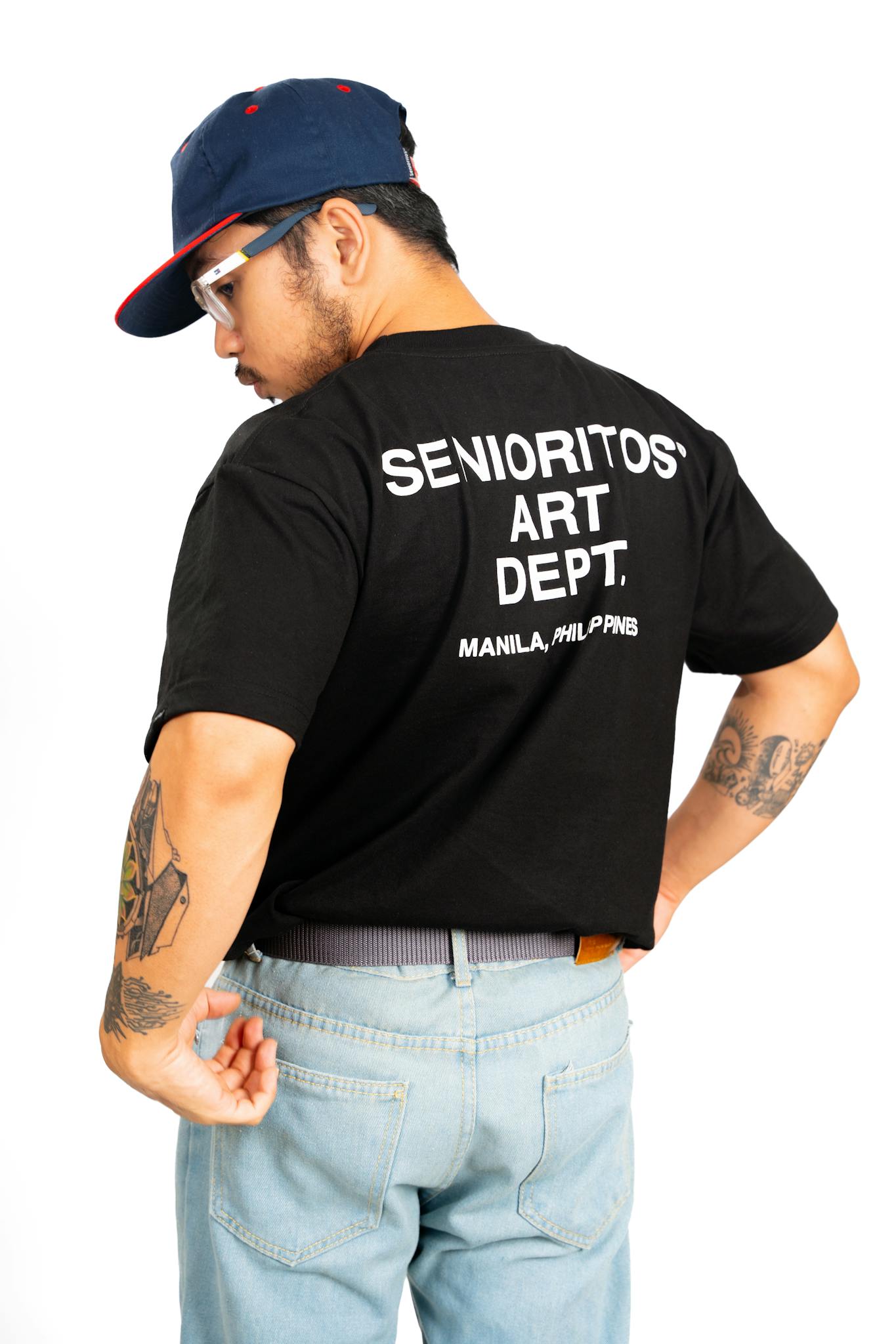 Young adult in graphic t-shirt and cap showcasing street fashion style.